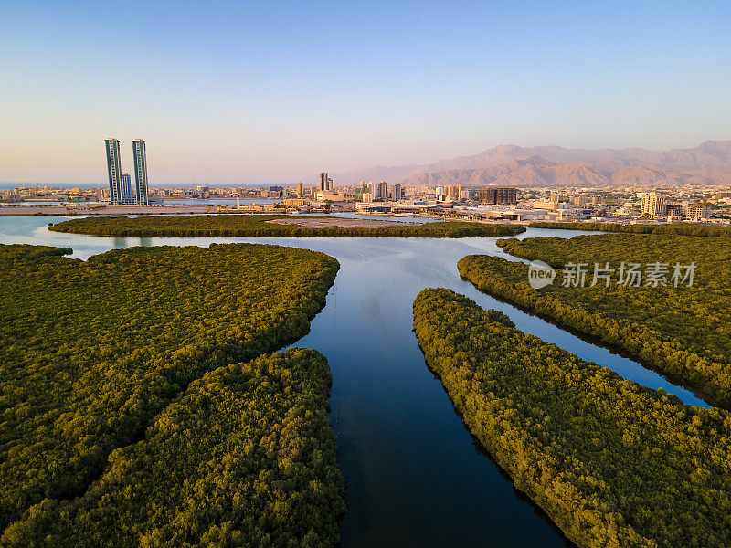 拉斯al Khaimah酋长国的城市天际线上升在红树林和小溪在阿拉伯联合酋长国日落